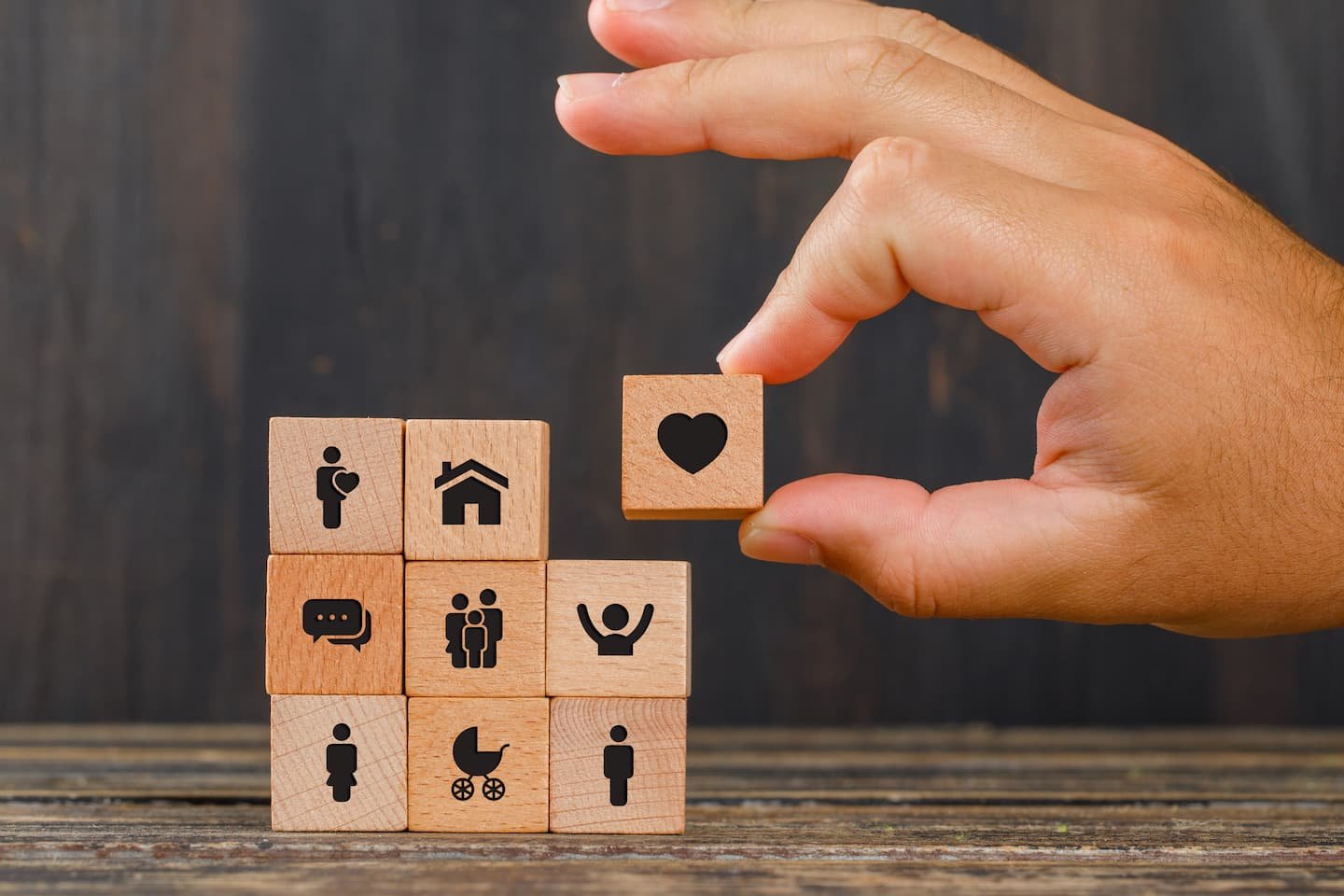 relationship-concept-wooden-table-side-view-hand-holding-wooden-cube-with-heart-icon (1)